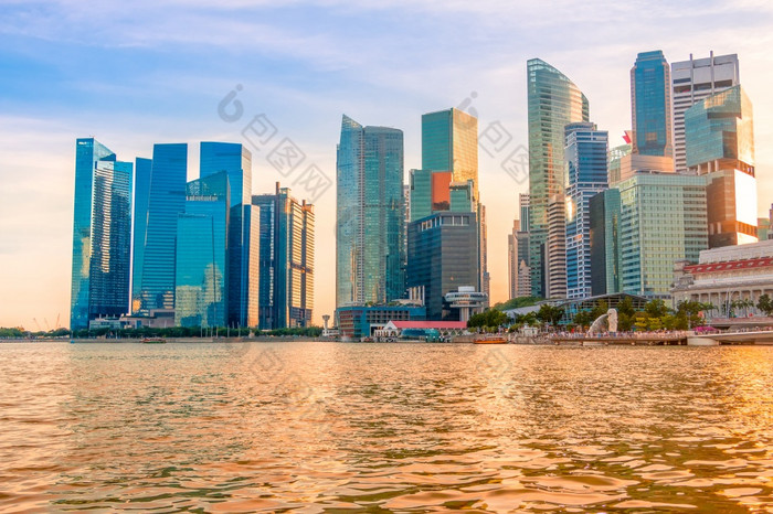 晚上新加坡摩天大楼的海岸玛丽娜湾的太阳染色的水金新加坡摩天大楼和金水日落