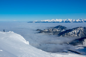 蓝色的天空和阳光明媚的天气在的雪山峰的山谷是<strong>密集</strong>的雾孤独的旅游照片的美雪山峰和雾的山谷