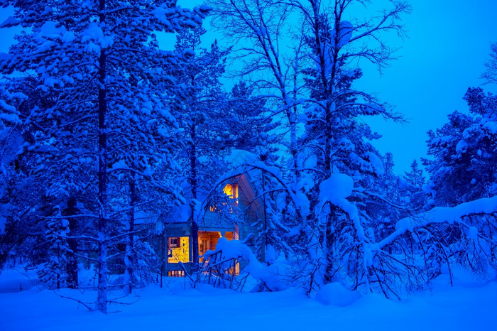 孤独的木小屋发光的晚上灌木丛的冬天森林很多雪点燃小屋的晚上雪森林