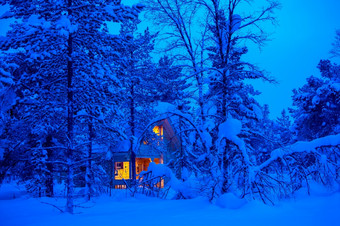 孤独的木小屋发光的晚上灌木丛的冬天森林很多雪点燃小屋的晚上雪森林