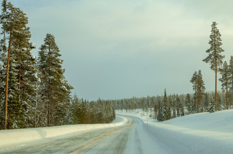冬天芬兰树木繁茂的山和很多雪空高速公路与飘的一边弱北部阳光空冬天高速公路通过树木繁茂的山