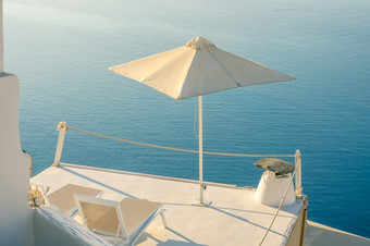 希腊安静的夏天晚上圣托里尼岛两个太阳便鞋和伞的<strong>阳台</strong>与海视图两个太阳便鞋和伞的<strong>阳台</strong>圣托里尼岛