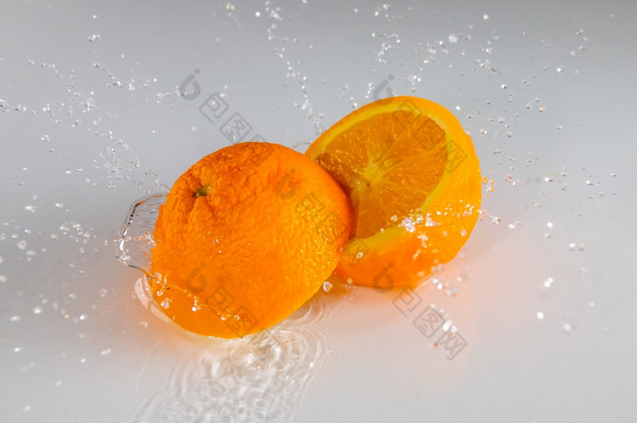 白色表格和薄层水两个半成熟的橙色和很多溅两个半橙色和很多水喷雾