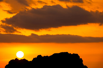 轮廓山峰日落太阳和云明亮的橙色天空明亮的橙色日落天空在的悬崖