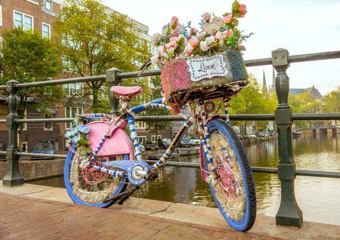 荷兰多云的早....的阿姆斯特丹运河flower-decorated自行车与爱标志停的桥栅栏爱自行车的栏杆的运河桥阿姆斯特丹