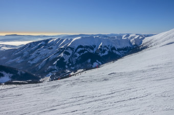 斯洛伐克冬天滑雪度假胜地明亮阳光明媚的天气和蓝色的天空在空宽滑<strong>雪坡</strong>山山峰和雾的地平线阳光明媚的天气在的滑<strong>雪坡</strong>和雾在的山山峰的地平线