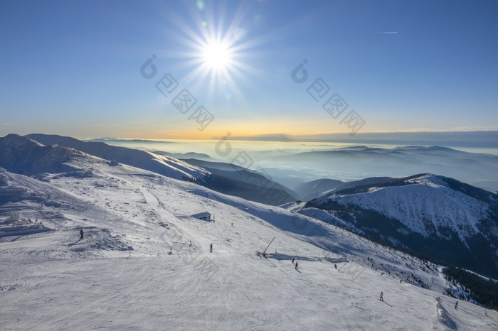 斯洛伐克冬天滑雪度假胜地明亮明亮的太阳的蓝色的天空在的滑雪坡山山峰和雾的地平线明亮的太阳在的滑雪坡和雾在的山山峰的地平线