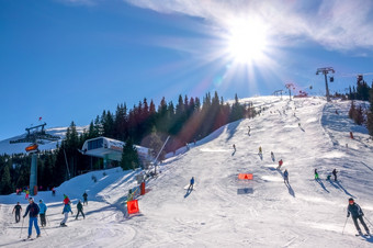 斯洛伐克冬天滑雪度假胜地明亮明亮的太阳的蓝色的天空以上的滑雪坡滑雪电梯和许多滑雪者明亮的太阳以上的滑雪度假胜地和许多滑雪者