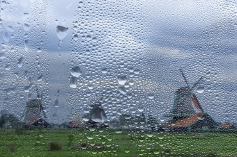 荷兰老风车的雍斯安多雨的天气视图通过窗口与雨滴视图通过多雨的窗口老风车的荷兰
