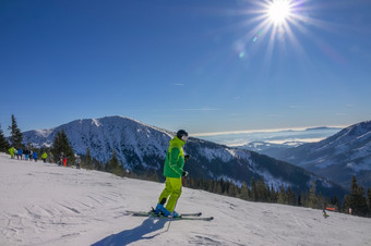 冬天阳光明媚的一天认不出来滑雪黄色的夹克<strong>游乐设施</strong>沿着宽滑雪坡滑雪黄色的滑雪西装阳光明媚的滑雪坡
