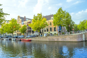荷兰<strong>春天</strong>一天的阿姆斯特丹运河船停泊的水和<strong>汽车</strong>的路堤<strong>春天</strong>的阿姆斯特丹运河