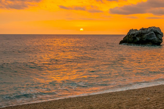 孤独的岩石的海附近的桑迪海滩色彩斑斓的日出在的平静水域的希腊地中海海岸孤独的岩石的海黎明和带桑迪海滩
