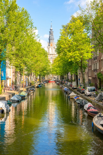 荷兰阳光明媚的夏天一天的阿姆斯特丹运河停汽车的路堤和许多停泊船的水大教堂建筑的距离阿姆斯特丹运河与船阳光明媚的一天