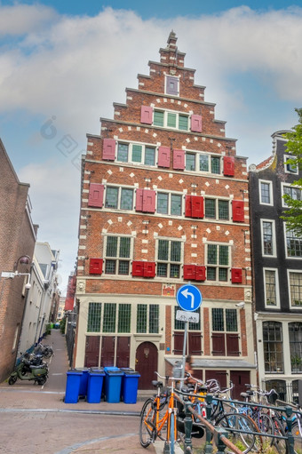荷兰狭窄的街道阿姆斯特丹与停自行车和摩托车典型的荷兰房子与红色的百叶窗的窗户狭窄的街道阿姆斯特丹和真实的房子