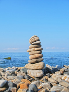 平衡石头的海滨夏季而且蓝色的天空背景