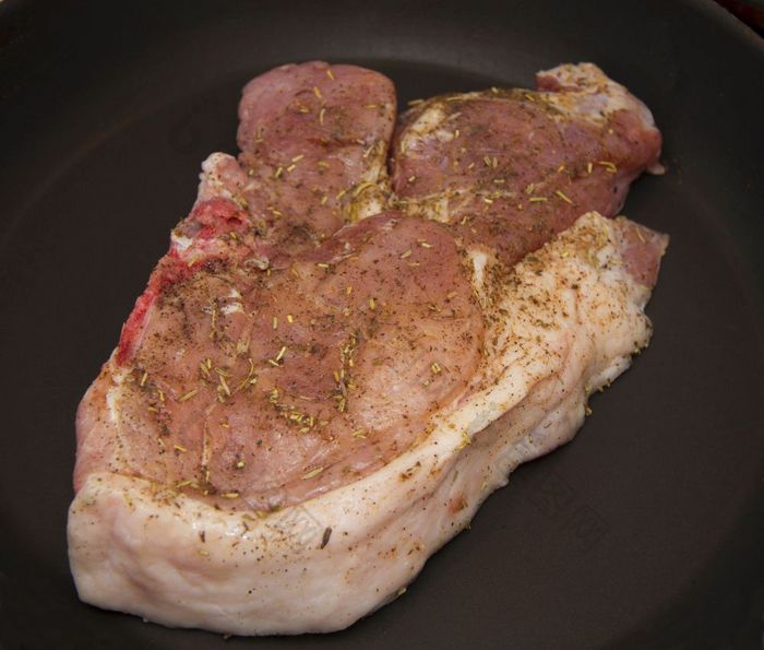 新鲜的生猪肉牛排与不同的香料烤的黑色的煎锅的厨房