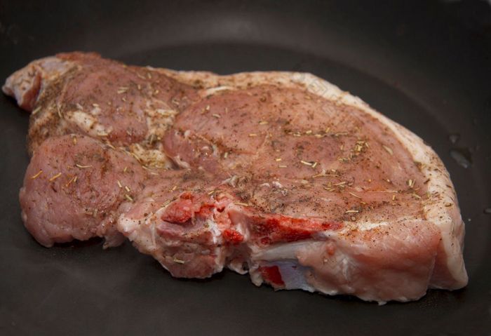 新鲜的生猪肉牛排与香料烤的黑色的煎锅的厨房