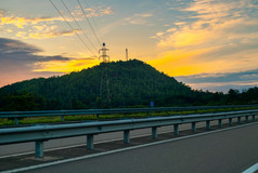 高速公路美丽的路边风景不断上升的太阳后面的山和领先的电线的山前塔