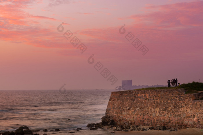 人放松和享受的视图的晚上波崩溃成的岩石的海岸长曝光照片神奇的日落云的地平线加勒堡斯里兰卡斯里兰卡