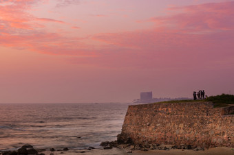 人放松和享受的视图的晚上波崩溃成的岩石的海岸长曝光照片神奇的日落云的地平线加勒堡斯里兰卡斯里兰卡