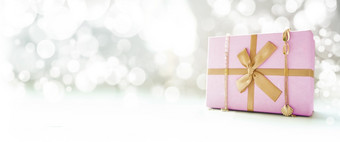 粉红色的礼物盒子与黄金丝带和黄金装饰散景背景一边视图复制空间