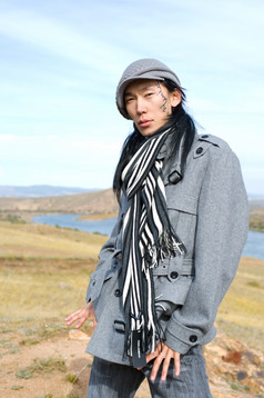 年轻的亚洲男人。灰色外套帽而且条纹黑白围巾的窗饰他的脸颊他的的名字Chinghis古老的蒙古