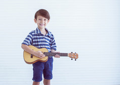 肖像高加索人小男孩玩吉他白色背景与复制空间