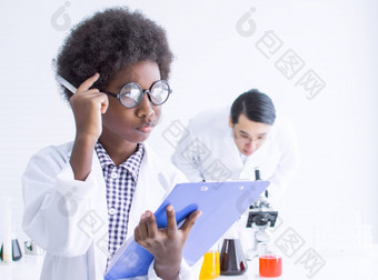 非洲黑色的小男孩穿眼镜研究科学教室学校和思考某物与模糊背景老师教育概念