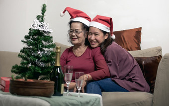 两个老妈妈。和女儿穿圣诞老人他拥抱和坐着生活房间首页圣诞节新一年庆祝活动概念