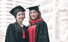 两个亚洲女学生穿统一的帽和微笑与幸福后毕业教育概念