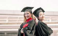 两个亚洲女学生穿统一的帽和微笑与幸福后毕业教育概念