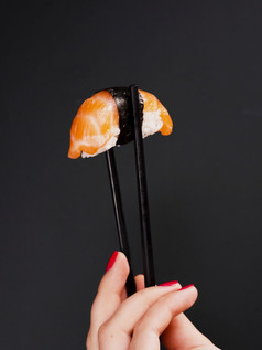 女人持有一对筷子与大马哈鱼寿司决议和高质量美丽的照片女人持有一对筷子与大马哈鱼寿司高质量美丽的照片概念