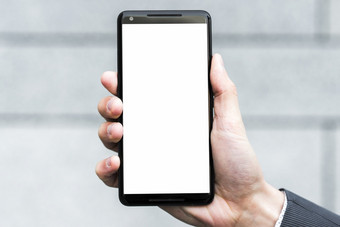 商人手显示白色显示屏幕智能手机对模糊背景决议和高质量美丽的照片商人手显示白色显示屏幕智能手机对模糊背景高质量美丽的照片概念