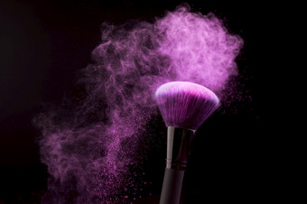 化妆刷与紫色的粉灰尘黑暗背景高决议照片化妆刷与紫色的粉灰尘黑暗背景高质量照片
