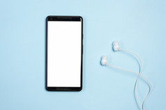 白色空白屏幕显示移动电话与耳机对蓝色的背景高决议照片白色空白屏幕显示移动电话与耳机对蓝色的背景高质量照片