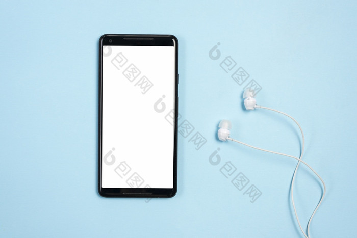 白色空白屏幕显示移动电话与耳机对蓝色的背景高决议照片白色空白屏幕显示移动电话与耳机对蓝色的背景高质量照片