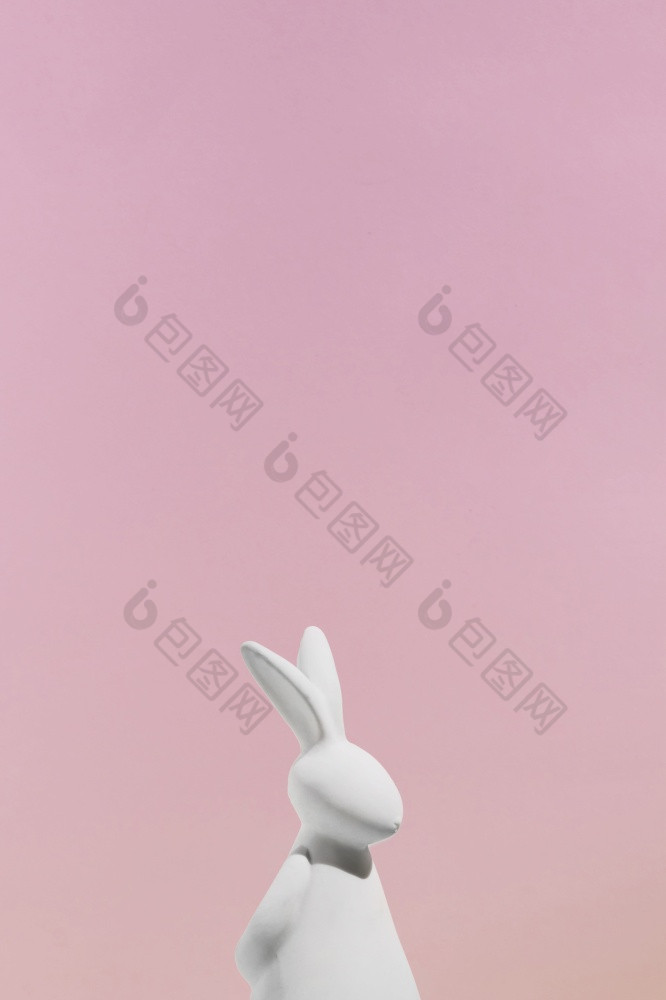 白色兔子小雕像粉红色的背景高决议照片白色兔子小雕像粉红色的背景高质量照片