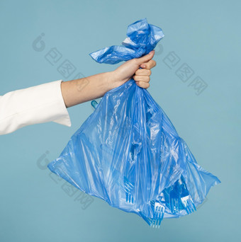女人持有蓝色的塑料垃圾袋高决议照片女人持有蓝色的塑料垃圾袋高质量照片
