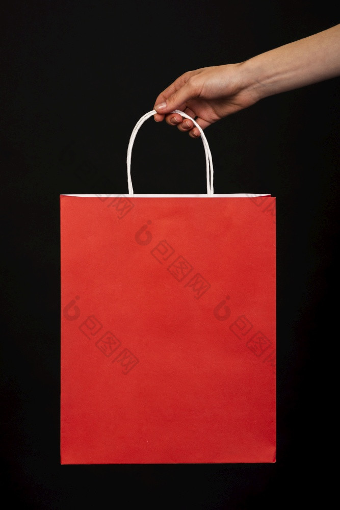 关闭手持有红色的购物袋黑色的背景高决议照片关闭手持有红色的购物袋黑色的背景高质量照片