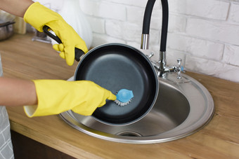 人手与黄色的手套洗锅与刷厨房