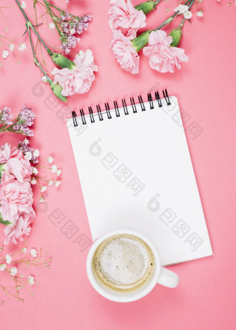 开销视图咖啡杯空白记事本与康乃馨满天星limonium花粉红色的背景