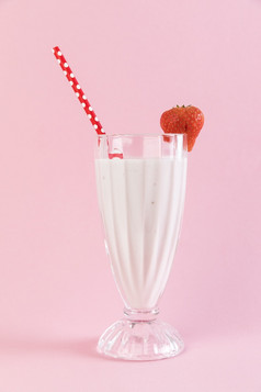 关闭草莓奶昔玻璃与粉红色的背景