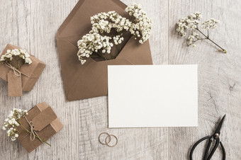 棕色（的）信封与婴儿呼吸花礼物盒子婚礼环剪刀白色卡木背景