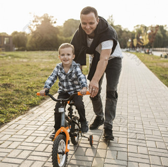 父亲帮助他的儿子骑自行车
