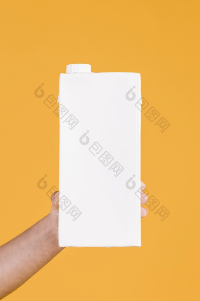 人类手持有白色牛奶盒子黄色的背景