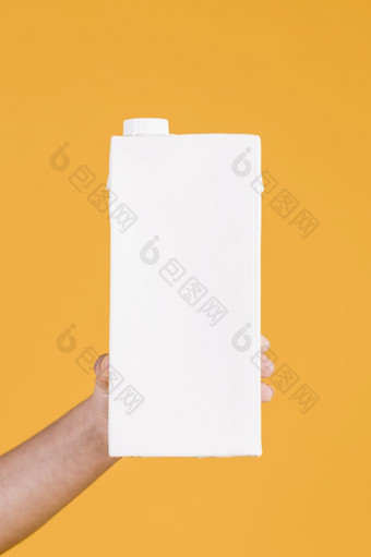 人类手持有白色<strong>牛奶盒</strong>子黄色的背景