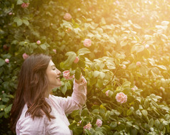 有吸引力的快乐女人持有粉红色的花日益增长的绿色嫩枝