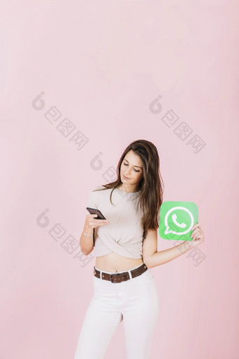 美丽的年轻的女人持有whatsapp图标使用移动电话