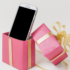 关闭手机装饰粉红色的礼物盒子对白色表面