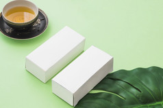 Herbal茶杯两个白色盒子与叶绿色背景
